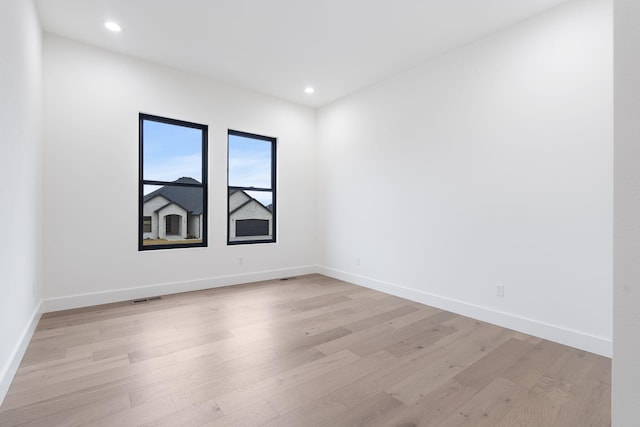 empty room featuring light wood-type flooring, visible vents, and baseboards