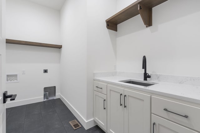 clothes washing area featuring hookup for a washing machine, hookup for an electric dryer, a sink, visible vents, and baseboards