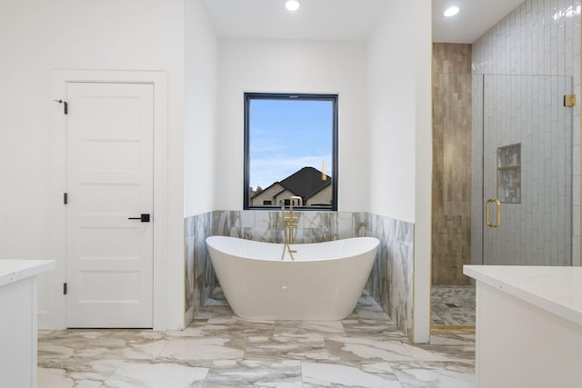 full bathroom with marble finish floor, a shower stall, a freestanding bath, and vanity