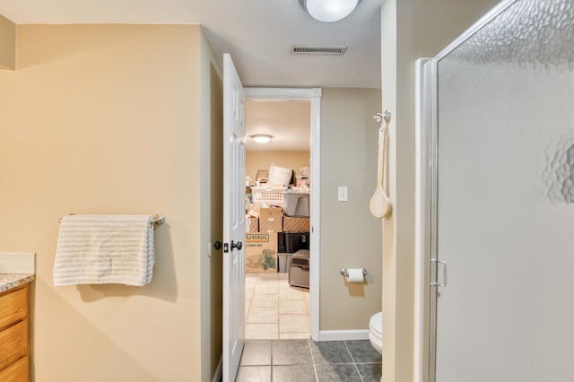 bathroom with tile patterned flooring, toilet, vanity, baseboards, and a shower stall