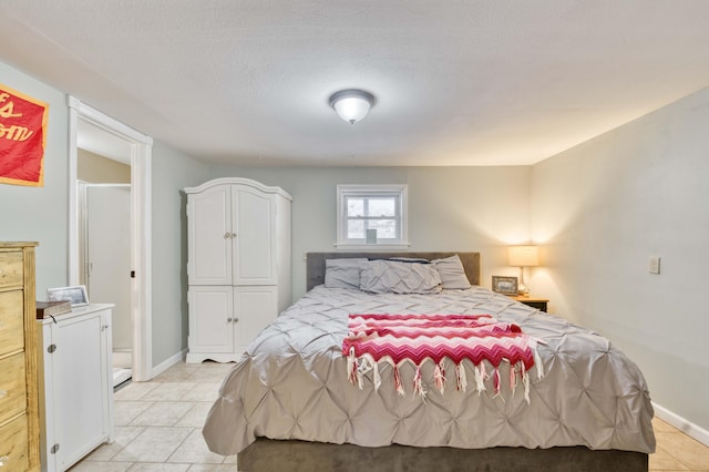 bedroom with a textured ceiling, light tile patterned flooring, and baseboards