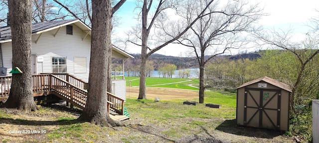 view of yard featuring a water view, an outdoor structure, stairway, and a storage shed