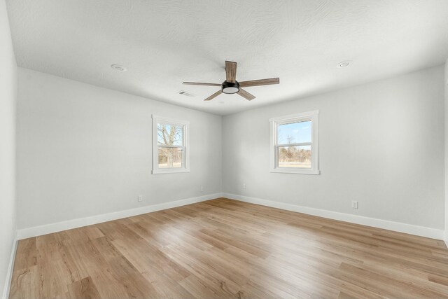 empty room with a ceiling fan, light wood-type flooring, and baseboards