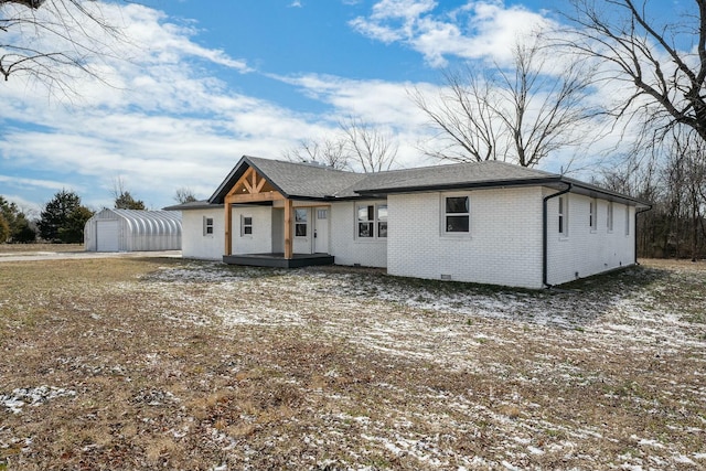 view of front of house featuring an outbuilding, crawl space, brick siding, and roof with shingles