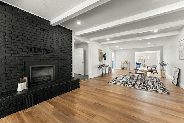 living room with baseboards, wood finished floors, a fireplace, beam ceiling, and recessed lighting