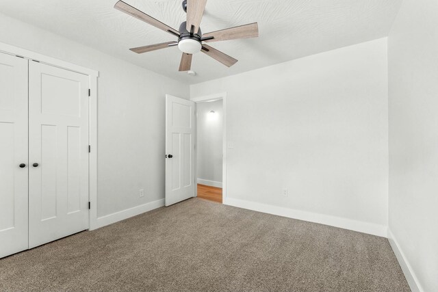 unfurnished bedroom featuring a ceiling fan, carpet, a closet, and baseboards