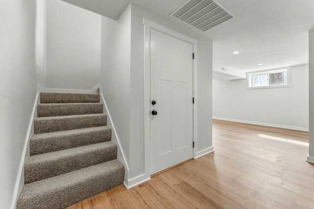 stairs with recessed lighting, wood finished floors, visible vents, and baseboards