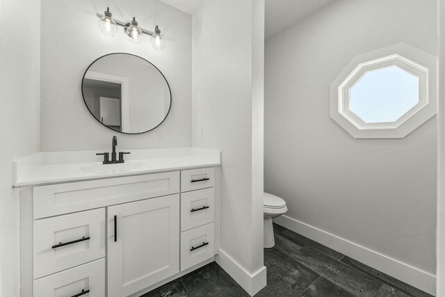 bathroom featuring baseboards, vanity, toilet, and wood finished floors