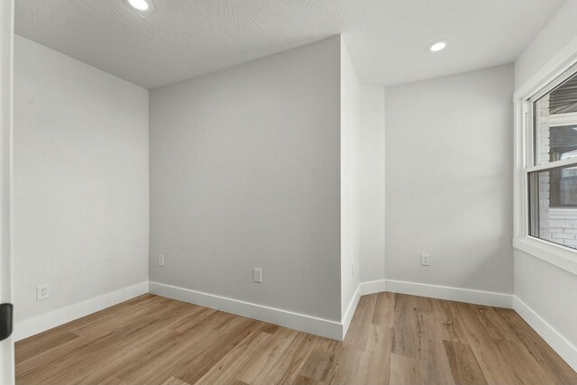 spare room featuring light wood-type flooring, baseboards, and recessed lighting