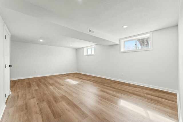 below grade area with visible vents, recessed lighting, light wood-style flooring, and baseboards