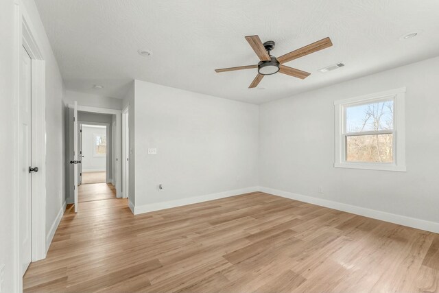 spare room featuring a ceiling fan, light wood-style flooring, visible vents, and baseboards