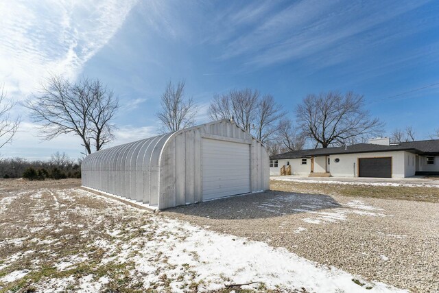 snow covered garage featuring a garage and gravel driveway