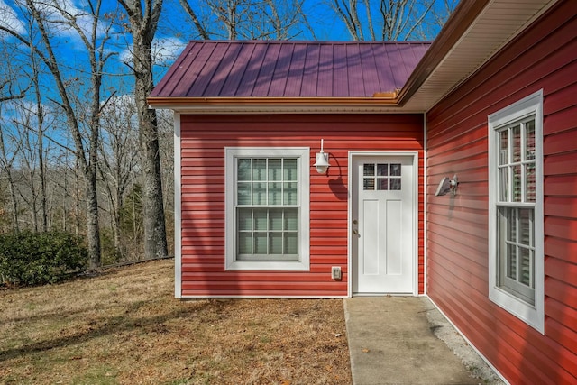 doorway to property with a standing seam roof, metal roof, and a lawn