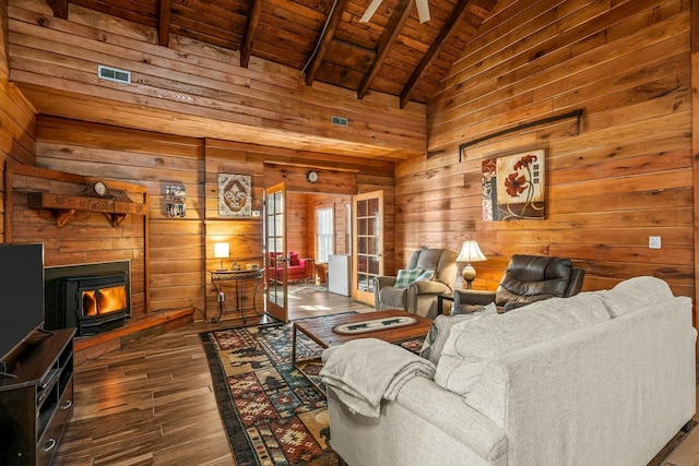 living room with dark wood-style floors, wood ceiling, wooden walls, and a wood stove