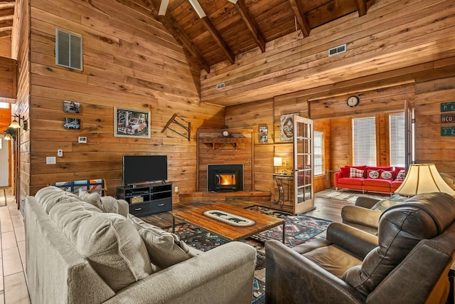 living room featuring beam ceiling, visible vents, light wood-style flooring, wood walls, and wooden ceiling