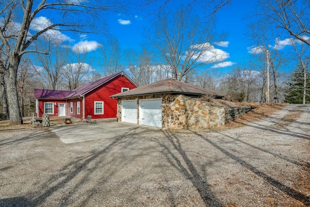 view of property exterior featuring stone siding, driveway, and an attached garage