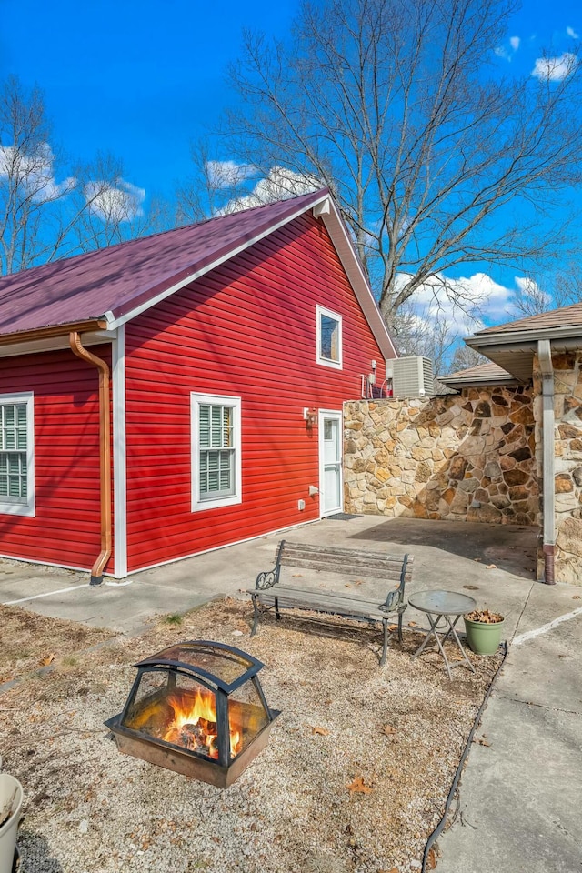 view of side of property featuring a fire pit and central AC