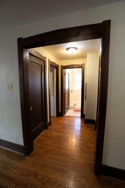 hallway featuring dark wood-style floors and baseboards