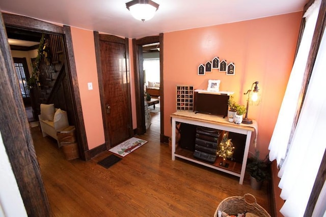 corridor featuring stairs, dark wood-type flooring, and baseboards