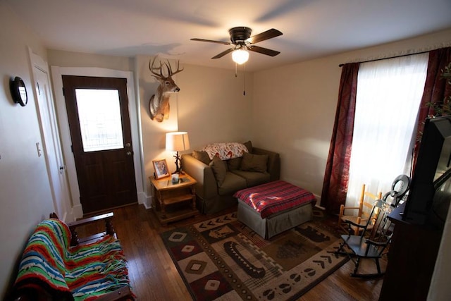 living area featuring a ceiling fan and dark wood-style flooring