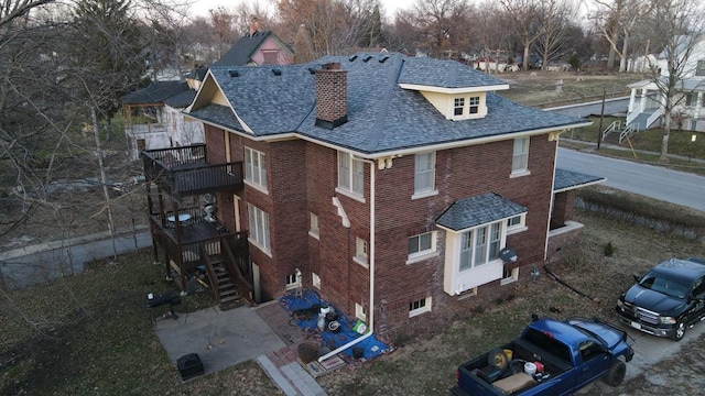 exterior space featuring a shingled roof, brick siding, and a chimney