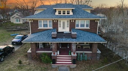 bungalow-style home with covered porch and brick siding