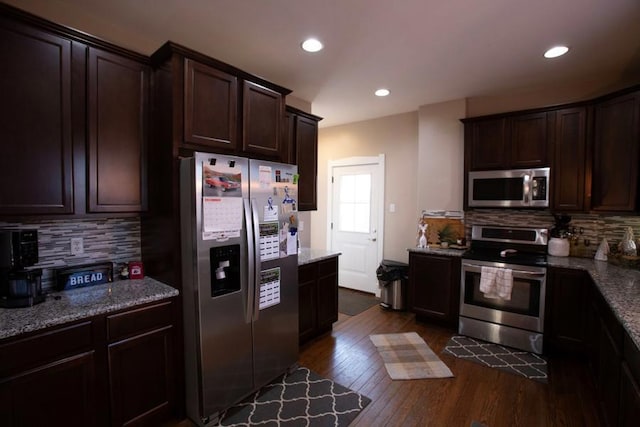 kitchen featuring stainless steel appliances, dark brown cabinets, dark wood-style flooring, and light stone countertops