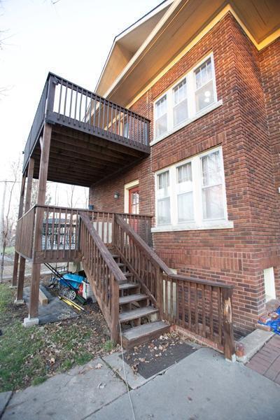 view of property exterior featuring a deck, brick siding, and stairway