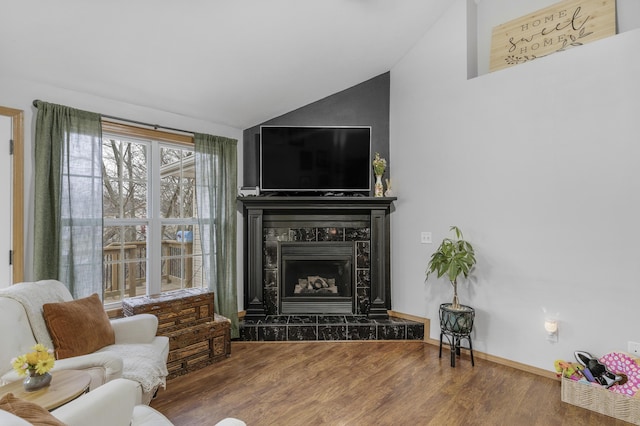 living area featuring lofted ceiling, baseboards, a tiled fireplace, and wood finished floors