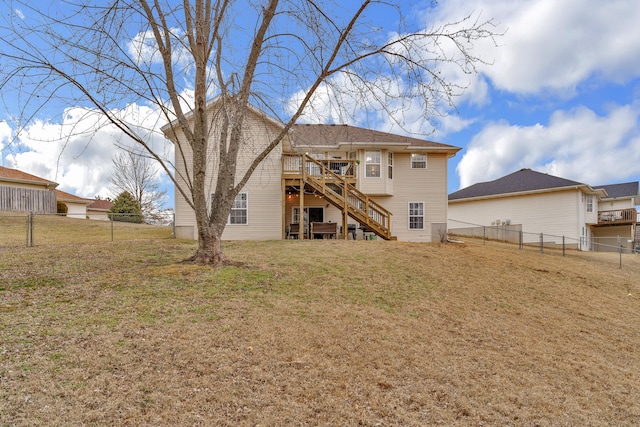 rear view of house featuring a fenced backyard, stairs, a lawn, and a wooden deck