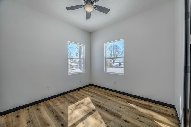 unfurnished room featuring ceiling fan, light wood-style flooring, and baseboards