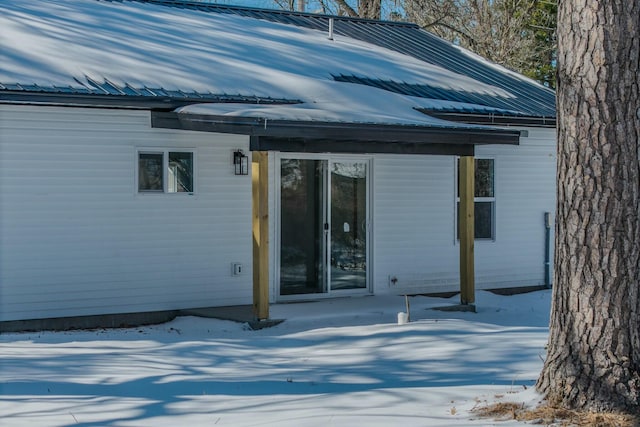 snow covered house featuring metal roof