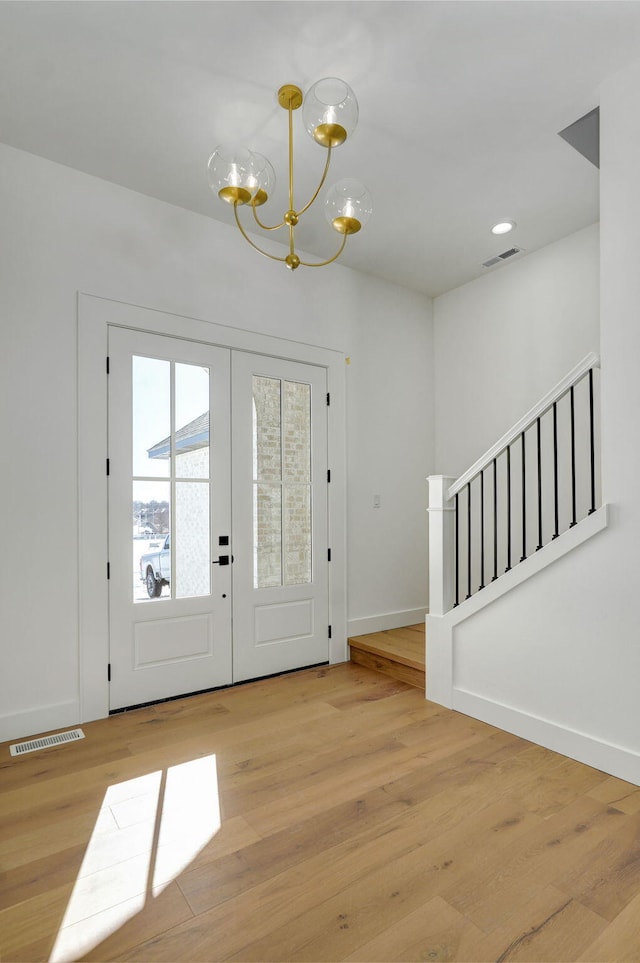 entrance foyer featuring light wood finished floors, visible vents, stairway, an inviting chandelier, and french doors