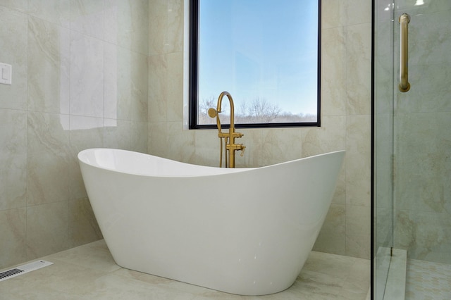 full bathroom with tile walls, a soaking tub, visible vents, a tile shower, and tile patterned floors