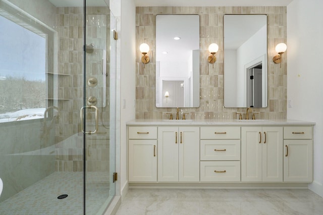 bathroom with marble finish floor, double vanity, a sink, and a shower stall