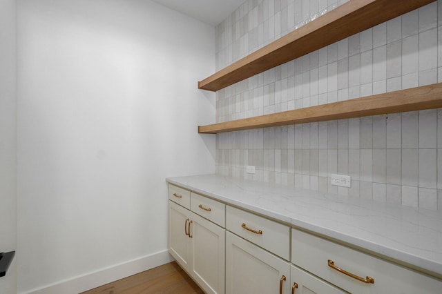 bar featuring tasteful backsplash, light wood-style flooring, and baseboards