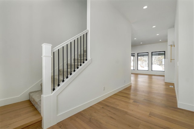 staircase featuring baseboards, wood finished floors, and recessed lighting