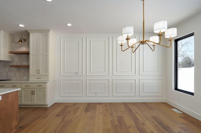 unfurnished dining area with a wealth of natural light, light wood-style flooring, visible vents, and baseboards