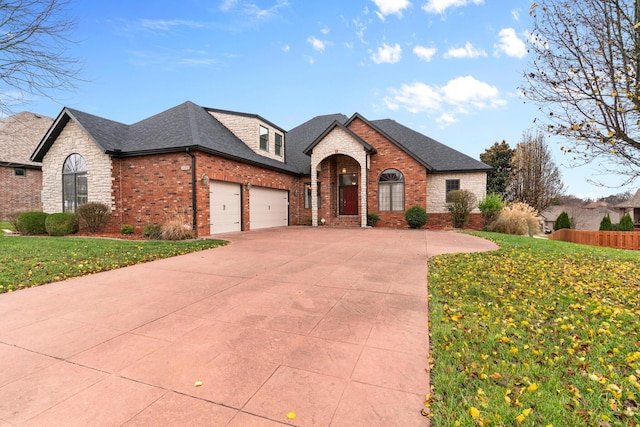 french provincial home with a garage, a shingled roof, concrete driveway, a front lawn, and brick siding