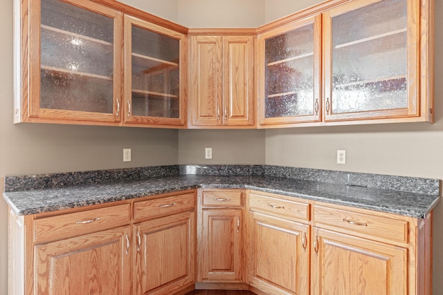 kitchen featuring dark stone counters and glass insert cabinets