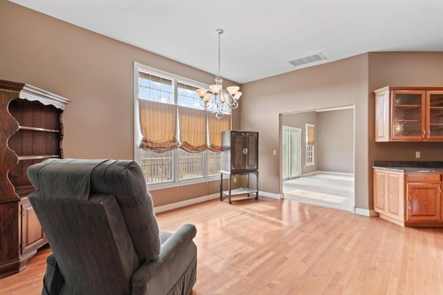 living area featuring a chandelier, a wealth of natural light, visible vents, and light wood finished floors