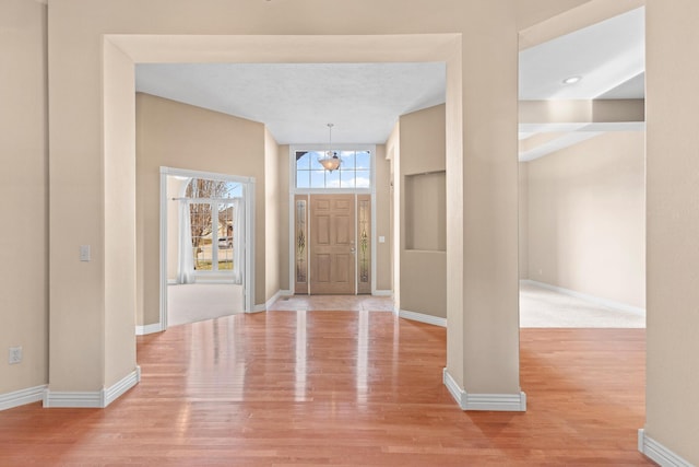 entryway featuring light wood finished floors, baseboards, and a textured ceiling