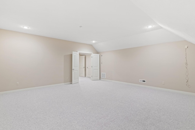 interior space featuring lofted ceiling, visible vents, light carpet, and baseboards