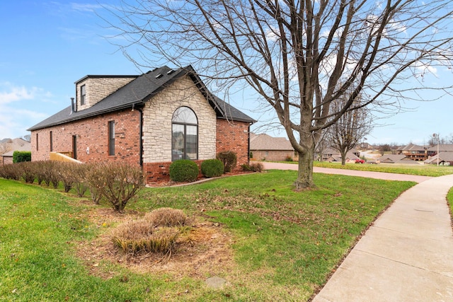 view of side of property with a yard, roof with shingles, stone siding, and brick siding