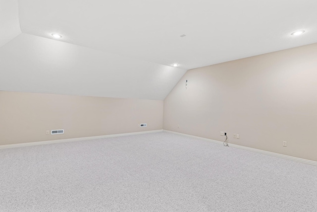 additional living space with lofted ceiling, light carpet, visible vents, and baseboards