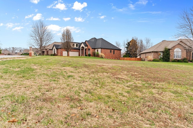 view of front of house with a front yard, brick siding, fence, and an attached garage