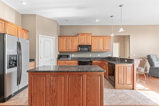 kitchen featuring dark stone counters, a kitchen island, hanging light fixtures, a peninsula, and black appliances