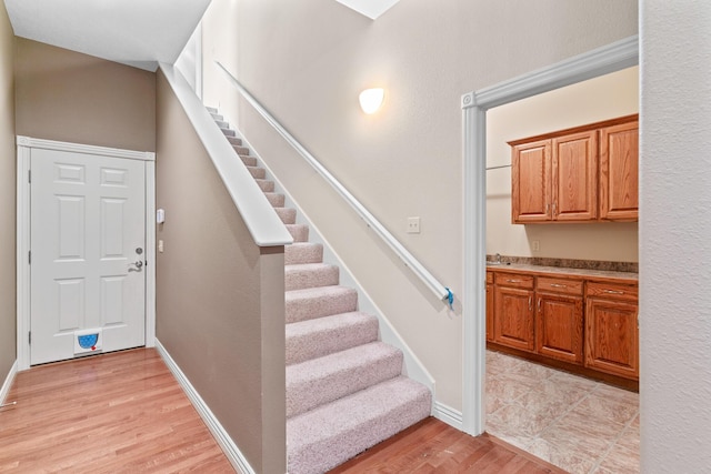 staircase featuring wood finished floors and baseboards