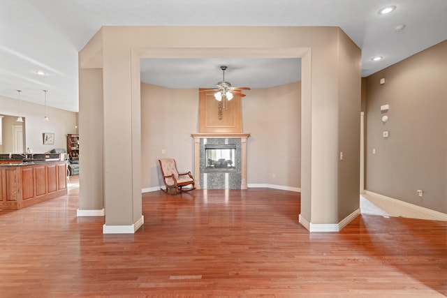 interior space featuring recessed lighting, a fireplace, a ceiling fan, baseboards, and light wood-type flooring