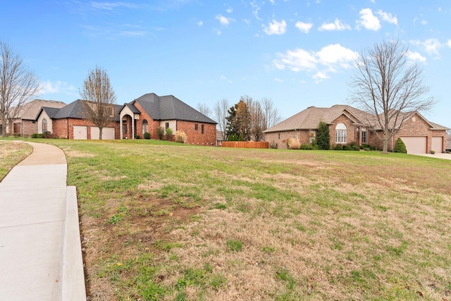 view of front facade with an attached garage, fence, a front lawn, and brick siding